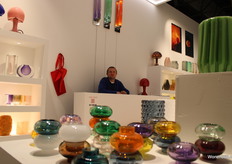 Eigenaar Ju bij de stand van Ju. Hij liet verschillende nieuwe glazen accessoires, lampen en poefjes zien.
