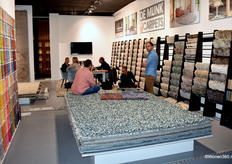 Een blik in de stand van De Munk Carpets, waar de accountmanagers John Brugge (achter de tafel) en Luuk Oosterbaan (2e van rechts) klanten van de laatste nieuwigheden op de hoogte brengen.