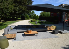 Op de buitenbank, liggen een aantal kussens van Jardinico die sneldrogend zijn. Tevens is de vernieuwde robuuste parasol te zien, die een voet heeft van 300 kilo.