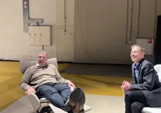 Een bezoeker test een fauteuil terwijl Rob lachend toekijkt.