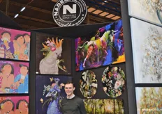 Bart van Gils bij enkele kleurrijke schilderijen van Narel, een onlangs opgerichtte groothandel in schilderijen.